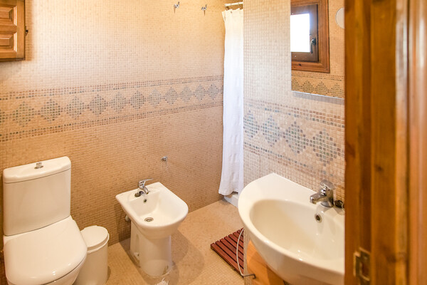 Baño completo con bidet y paredes alicatadas en tonos crema en la casa rural Pariseo