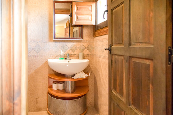 Lavabo con mueble de madera y espejo en uno de los 9 baños de la estancia en Soria