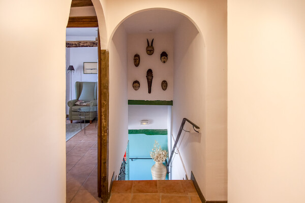 Acceso a plantas superiores con arcos tradicionales y decoración de máscaras étnicas