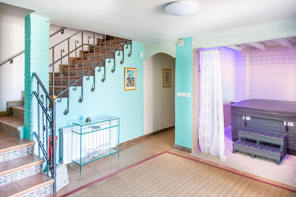 Zona de relax con jacuzzi privado y escaleras de forja en el interior de la casa