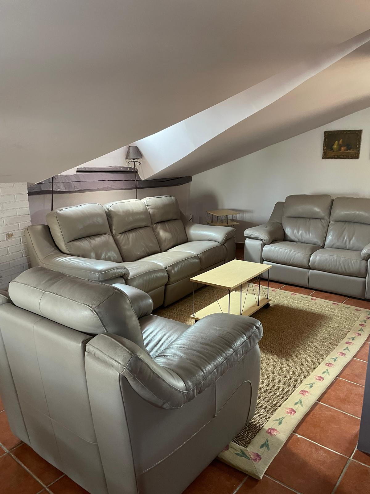 Salón abuhardillado con cómodos sofás de piel y ambiente acogedor en la planta superior