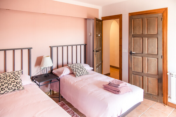 Dormitorio con detalles en rosa y luz cálida perfecto para una estancia familiar en Villalba